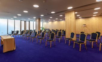 a conference room with rows of chairs arranged in a semicircle , and a projector on the wall at Sea Porto Hotel