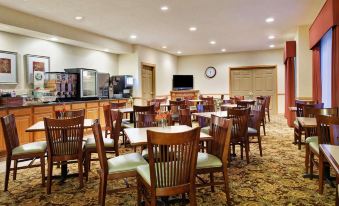 a large dining room with wooden tables and chairs , a television , and a clock on the wall at Country Inn & Suites by Radisson, Rock Falls, IL