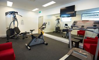 a gym with various exercise equipment and a tv screen on the wall , giving it a sleek and modern appearance at Quest Werribee