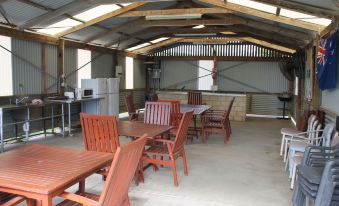a large wooden building with an open - air kitchen and dining area , featuring several tables and chairs at Seaspray Beach Holiday Park