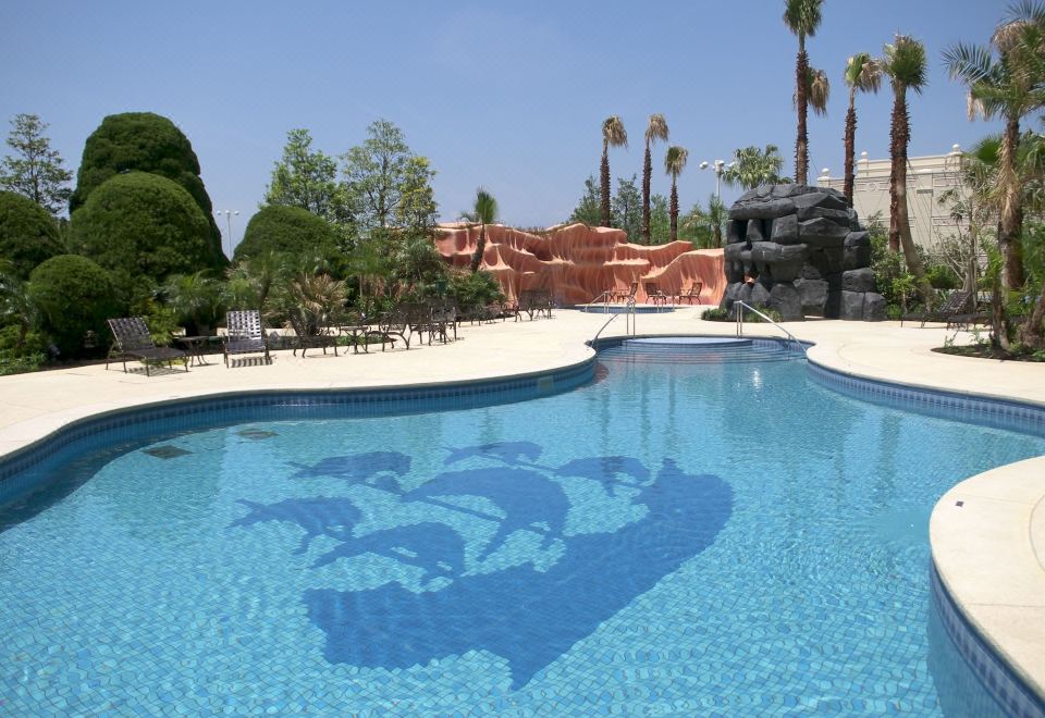 a swimming pool with palm trees and rocks , and a large image of a fish underwater in the water at Tokyo Disneyland Hotel