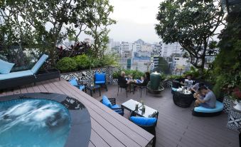 a rooftop patio with a hot tub surrounded by lounge chairs and a dining table at Alagon Saigon Hotel & Spa
