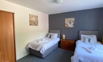 a hotel room with two beds , a nightstand between them , and a painting on the wall at Burlton Inn