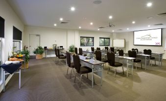 a large conference room with multiple tables and chairs arranged for a meeting or event at Mercure Clear Mountain Lodge