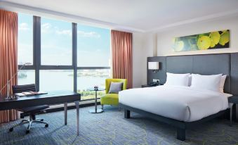 a hotel room with a king - sized bed , a desk , a chair , and a large window overlooking the water at Hilton Garden Inn Puchong