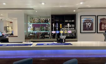 a modern bar with blue and white striped chairs , a large bar , and various bottles and glasses at Holiday Inn Express Burnley M65, Jct.10