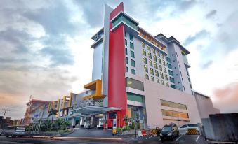 a large , modern hotel building with a red and yellow facade , situated on a busy street at Grand Artos Hotel & Convention