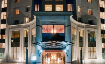 a large hotel entrance with a lit - up sign and two balconies , illuminated at night at Tunis Grand Hotel