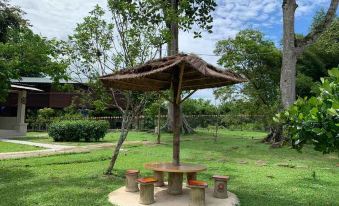 a large outdoor umbrella with a thatched roof is set up over a table and chairs in a park at Happy Paradise