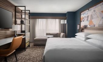 a modern hotel room with a white bed , couch , and desk , as well as blue walls and a large window at Marriott Boston Quincy
