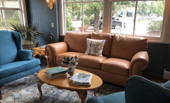 a living room with a brown leather couch , blue chairs , and a wooden coffee table at Magnolia Inn