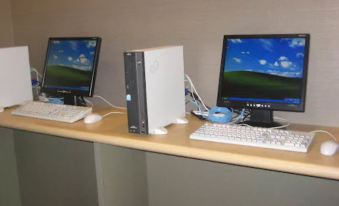 a desk with two computer monitors , keyboards , and a printer , all set up for use by a person at Meitetsu Inn Kariya