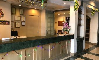 a hotel reception area with a counter and green decorations , including a sign for the reception at The Executive Hotel Lahad Datu