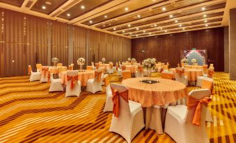 a large dining room filled with round tables and chairs , all covered in white tablecloths at Aloft New Delhi Aerocity