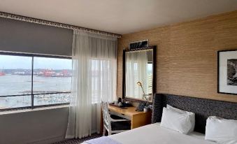 a hotel room with a large window overlooking a body of water , creating a serene atmosphere at The Royal Hotel by Coastlands Hotels & Resorts