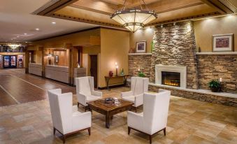 a spacious living room with white couches and chairs arranged around a fireplace , creating a cozy atmosphere at DoubleTree by Hilton Seattle Airport