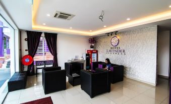 a modern and spacious reception area with a black couch , chairs , and a vending machine at Hotel Lavender Senawang