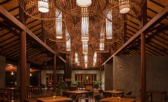 a large dining room with wooden tables and chairs , along with bamboo walls and ceiling at Azalea Village