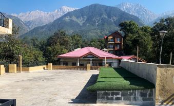 a large building with a red roof is surrounded by a green lawn and mountains in the background at The Sojourn