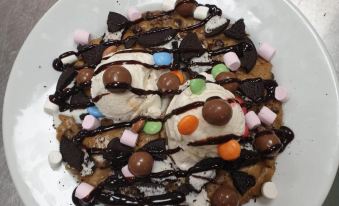 a white plate filled with a variety of toppings , including ice cream and marshmallows , placed on a dining table at North Devon Resort