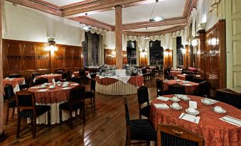a large , empty banquet hall with wooden floors and high ceilings , featuring multiple dining tables and chairs arranged in an orderly fashion at Hotel Astoria