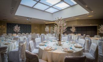 a large banquet hall with round tables set for a formal event , featuring white tablecloths , and a centerpiece of flowers at Harbour Hotel