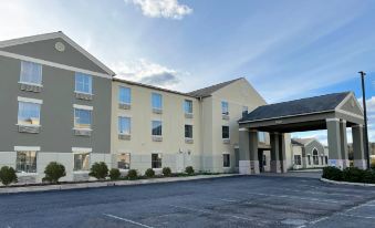 a large , modern hotel building with multiple stories and a parking lot in front of it at Wingate by Wyndham Clearfield