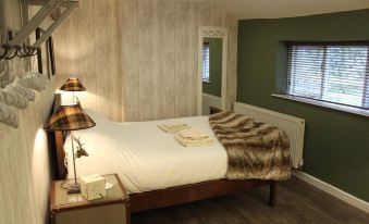 a neatly made bed with a furry blanket in a room with green walls and wooden floors at Beck Hall