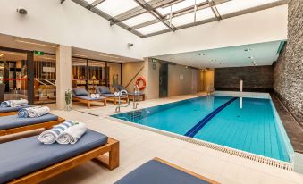 a large indoor swimming pool surrounded by lounge chairs and a hot tub , creating a relaxing atmosphere at Hilton Gdansk