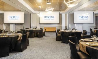 a conference room with multiple tables and chairs arranged for a meeting or event , along with large screen displays at Mantra Mooloolaba Beach