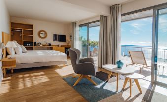 a modern hotel room with a large window overlooking the ocean , featuring a bed , chair , and table at Hotel la Villa Douce