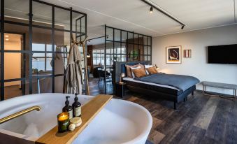 a modern bedroom with a large bed and a bathtub in the middle of the room at Pier 5 Hotel