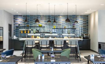 a modern restaurant with a bar area featuring a long counter , several chairs , and a dining table at NH Luxembourg