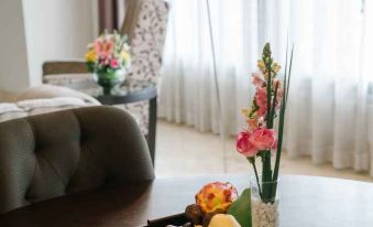 a living room with a couch , a coffee table , and a vase filled with flowers at Ascott Jakarta
