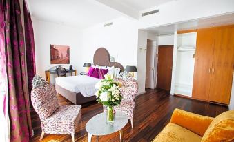 a spacious bedroom with hardwood floors , a king - sized bed , and a vase of flowers on a table at The Ambassador