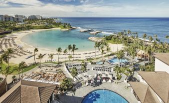 a beautiful resort with a large pool , palm trees , and a beach in the background at Four Seasons Resort Oahu at Ko Olina