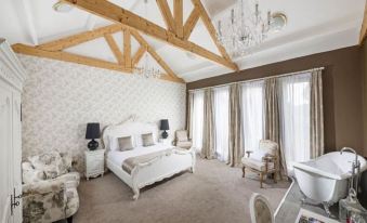a luxurious bedroom with a white bed , beige carpet , and wooden beams on the ceiling at The Cook and Barker Inn