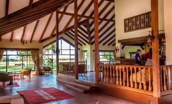 a large room with a wooden floor and high ceiling is filled with people working at a desk at Sweetwaters Serena Camp
