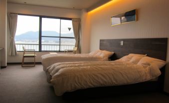 a hotel room with two beds , one on each side of the room , and a view of the ocean at Sakuraya