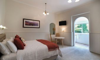 a cozy bedroom with a large bed , a television , and a door leading to a balcony at Windarra on High