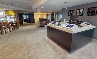a hotel lobby with a reception desk and a television mounted on the wall , creating an inviting atmosphere for guests at Village Hotel Cardiff