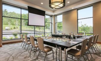 a conference room with multiple chairs arranged in a row , and a projector screen mounted on the wall at Embassy Suites by Hilton Berkeley Heights