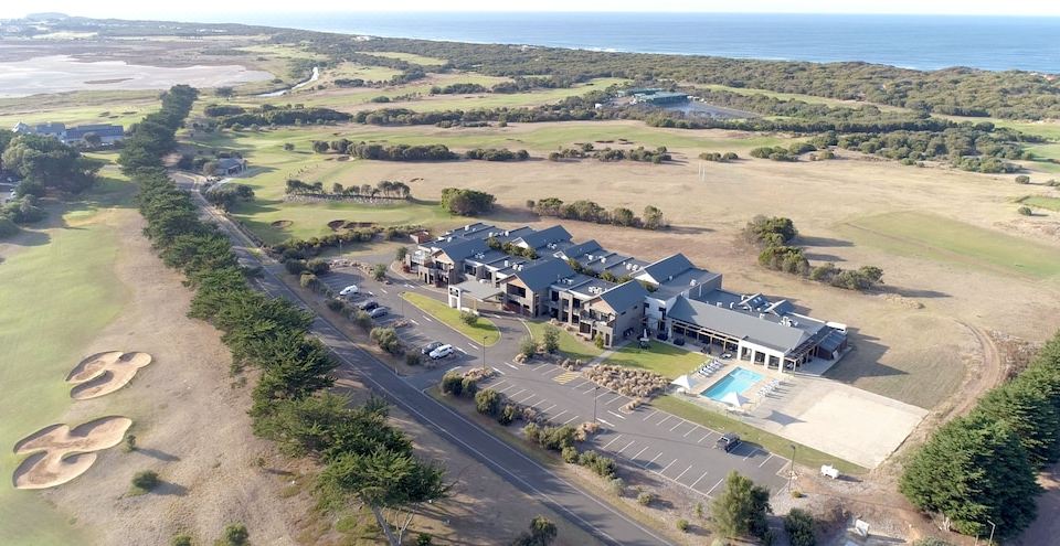 an aerial view of a large building with a swimming pool and parking lot , surrounded by grass and trees at Barwon Heads Resort