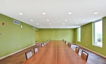 a large conference room with wooden tables and chairs , green walls , and recessed lighting , creating an open and inviting atmosphere at Home2 Suites by Hilton Helena