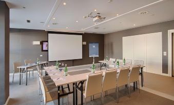 a conference room with a large table surrounded by chairs and bottles , ready for an event at NH Padova