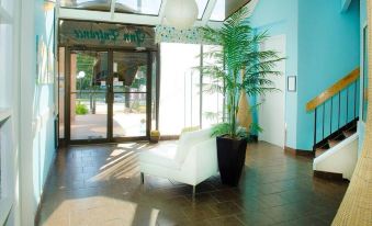 a white couch is sitting in a lobby with blue walls and a large plant at Thriftlodge Kingston