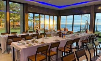 a large dining room with a long table set for a meal , overlooking the ocean at Blues River Resort