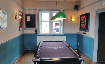 a pool table with a green felt top is in the middle of a room at Bulls Head