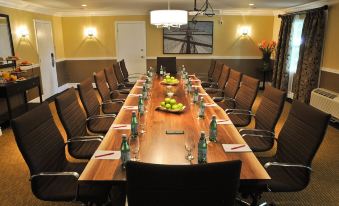 a long wooden conference table with brown chairs , surrounded by wine glasses , water bottles , and various food items at Oak Island Resort & Conference Centre