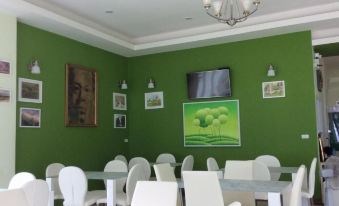 a dining room with a green wall , white chairs , and a television mounted on the wall at Greenseaviewresort Bangsaphan